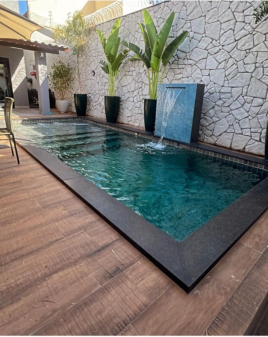Piscina grande ALB-KEV con muro de piedra, cascada y terminación en tonos oscuros para entretención